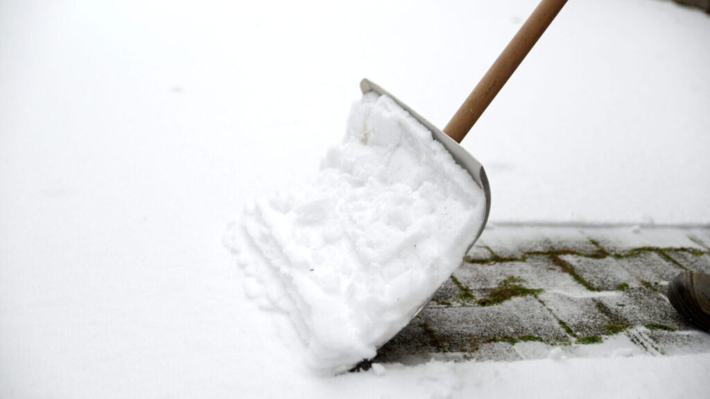 A snow shovel clearing snow from a paved path
