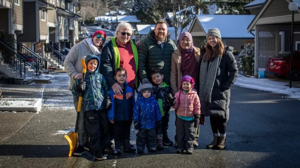 Families with young children standing on a townhouse street in winter